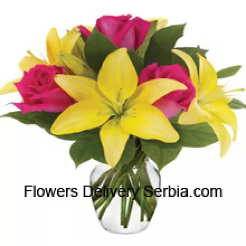 Roses roses et lys jaunes avec des remplisseurs saisonniers disposés magnifiquement dans un vase en verre