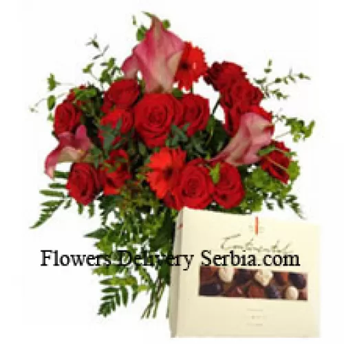 Gerberas rojas y rosas rojas en un jarrón junto con una caja de chocolate